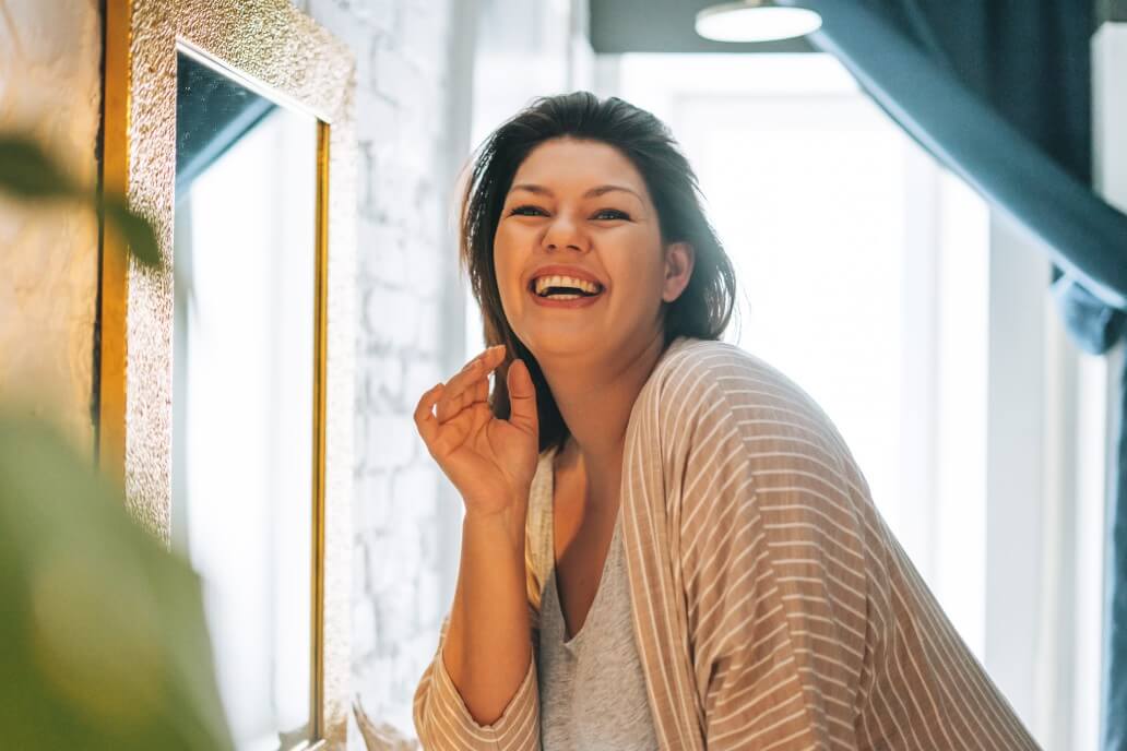 Beautiful smiling young woman plus size body positive in home in morning light