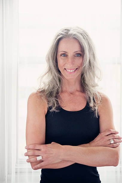 Woman in black dress smiling with arms crossed