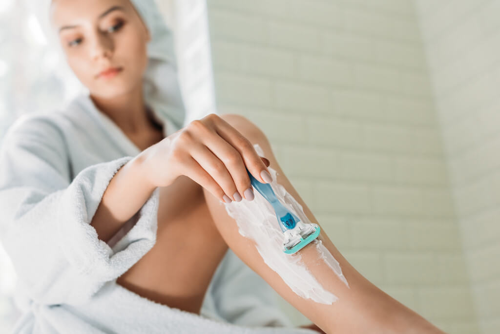 Woman shaving legs in bathroom