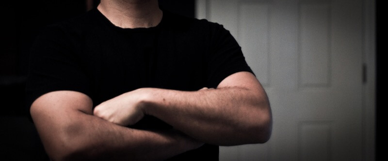 man in black t-shirt with crossed arms